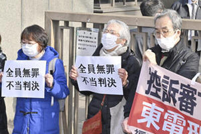 東京高裁判決を受け「全員無罪」と書かれた紙を掲げる福島原発刑事訴訟支援団のメンバーら＝１月１８日、東京高裁前