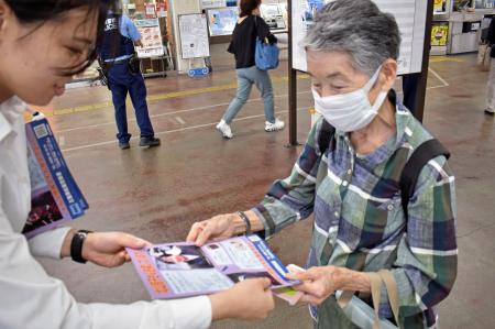 　ＪＲ松阪駅で情報提供を呼びかけるチラシを受け取る女性＝１３日午前、三重県松阪市