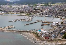 　漁船を出港させるのに必要な水深を確保するために海底の土砂をさらうしゅんせつ作業が進む、地震で海底が隆起した輪島港。奥は「輪島朝市」などの市中心部＝２６日午前、石川県輪島市（共同通信社ヘリから）