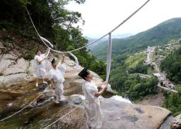 　「那智の滝」の上に架かるしめ縄を張り替える熊野那智大社の神職＝９日午前、和歌山県那智勝浦町