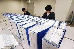 　２０２３年分の政治資金収支報告書（総務相所管の中央分）。奥はチェックする職員＝総務省